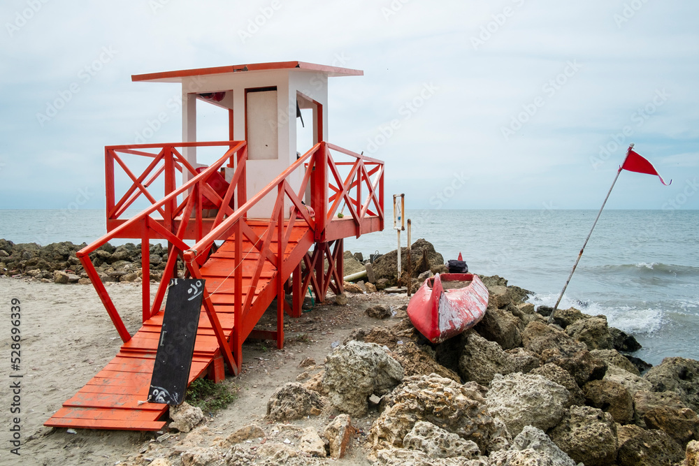 Lifeguard booth on the beach next to a canoe with the ocean in the background Lifeguard booth on the beach next to a canoe with the ocean in the background