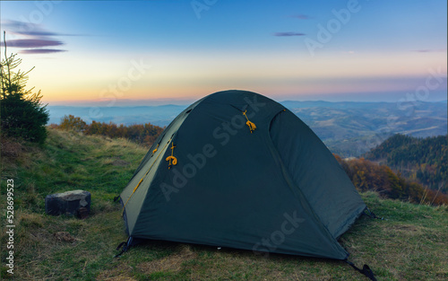 Green tourist tent against the background of an evening mountain landscape
