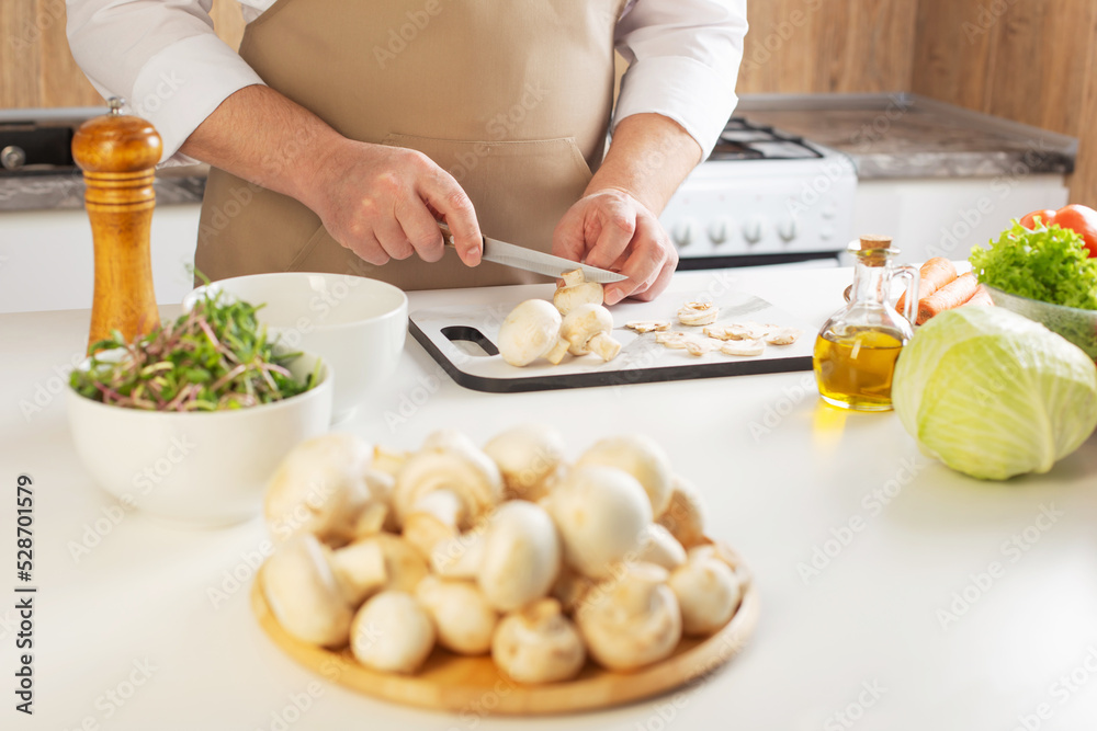 man cuts champignons on the table in the kitchen man cuts champignons on the table in the kitchen