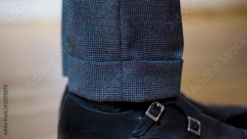 Side view close up of suit trousers cuff and patent shoes with straps.