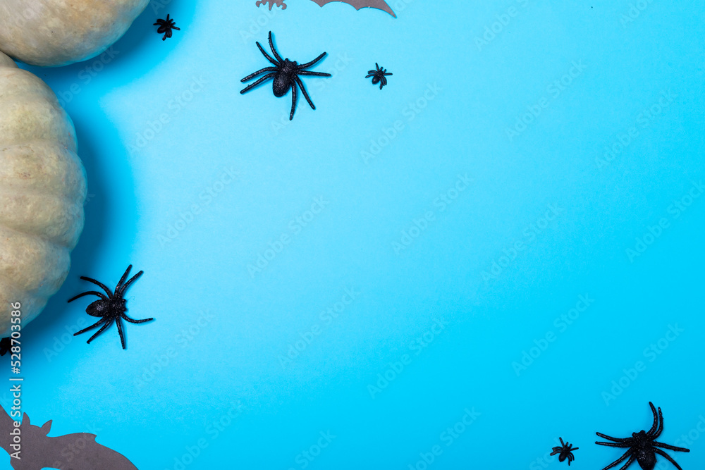 Pumpkins, multiple spider and bat toys with copy space on blue background