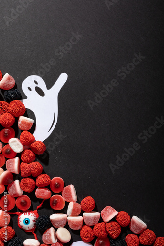 Halloween candies and ghost toy with copy space on grey background