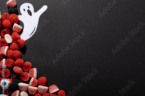 Multiple halloween candies and ghost toy with copy space on grey background