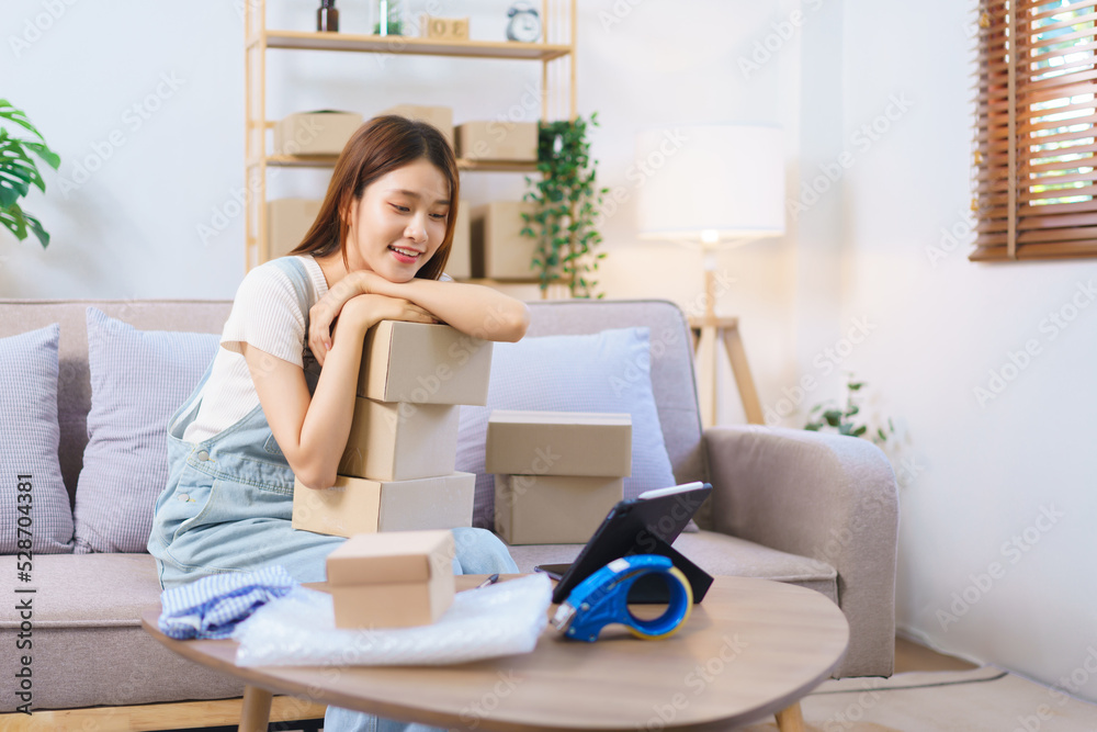 Online shopping concept, Female entrepreneur look data on tablet and prepare parcel boxes to client Online shopping concept, Female entrepreneur look data on tablet and prepare parcel boxes to client