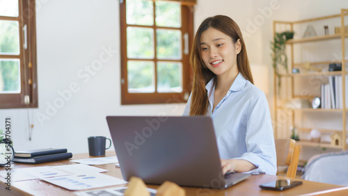 Business at home concept, Businesswoman use laptop to reading data and typing marketing plan report