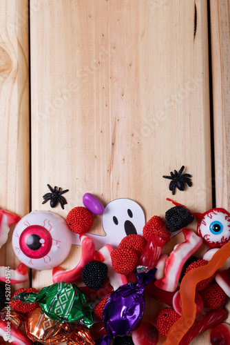 Multiple halloween toys and candies with copy space on wooden surface
