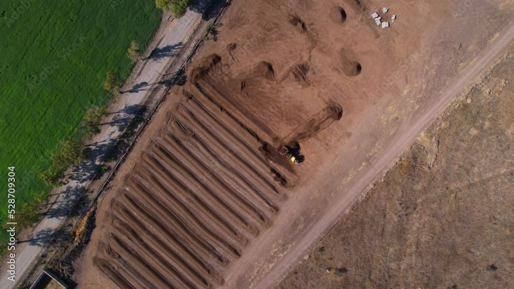 Aerial rotation of yellow tractor working with compost mixture on a farm in mexico Aerial rotation of yellow tractor working with compost mixture on a farm in mexico