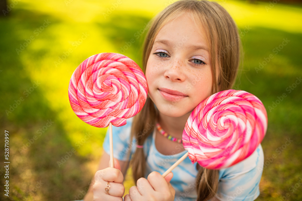 the child eats a bright lollipop. Beautiful girl model eats a bright