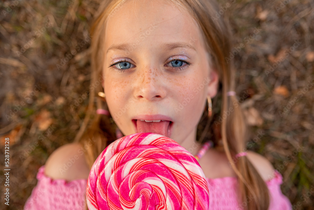 the child eats a bright lollipop. Beautiful girl model eats a bright