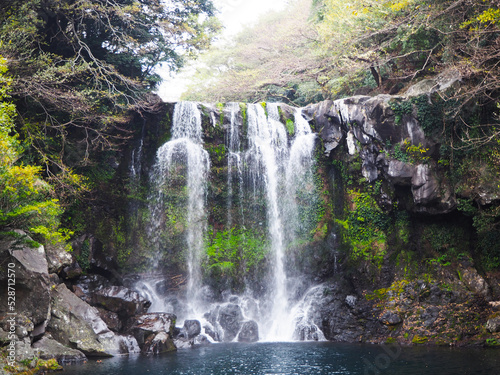 Cheonjeyeon waterfall flanked by rocks and trees in winter, Jeju Island, South Korea