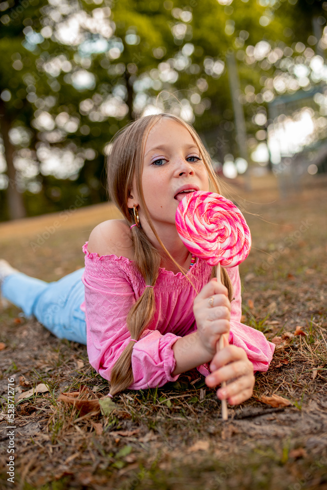the child eats a bright lollipop. Beautiful girl model eats a bright
