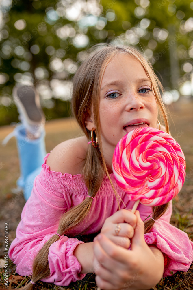 the child eats a bright lollipop. Beautiful girl model eats a bright