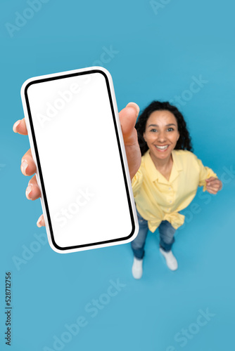 Above view of young woman pointing at mobile phone with blank screen, advertising website, offering space for ad mockup © Prostock-studio