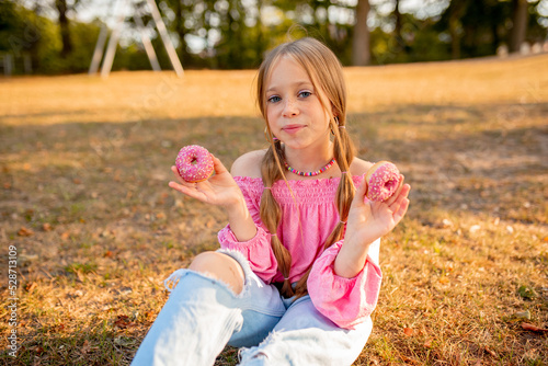  the child eats a donut. delicious pink donut. Bitten donut. Girl with donuts. Happy girl with freckles. Blue-eyed girl 