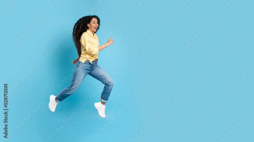 Cheerful Middle Eastern Woman Running In Mid Air, Blue Background