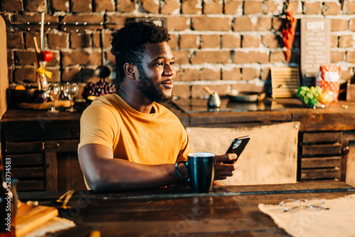 Male man hold mobile phone indoors in the room fool of green plants at sunny day light photo