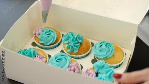 Pastry chef decorates cakes in box with blue cream. Close up. Concept of small home business and entrepreneurship.