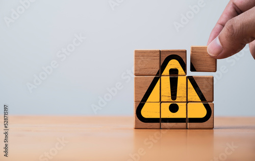 Hand assemble yellow exclamation caution sign or warning symbol print screen on wooden block on dark background for notification error and maintenance concept. photo