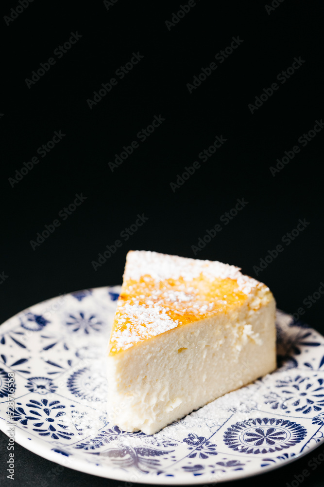 Piece of homemade cheesecake over a black background