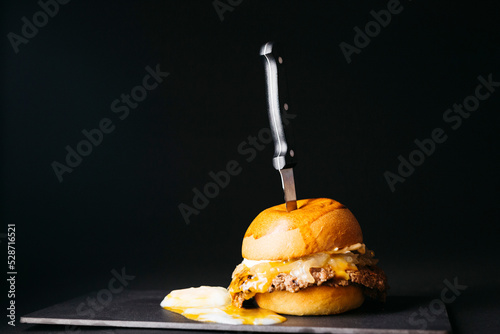 Doble smashburger with coocked onion and a boiled egg over a black background photo