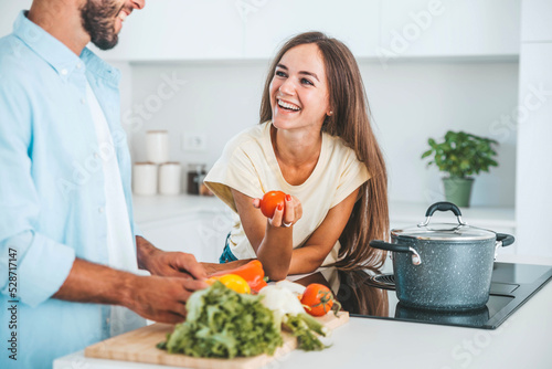 Young happy couple preparing healthy meal in kitchen at home - Husband and wife cooking salad - Food and healthy lifestyle concept