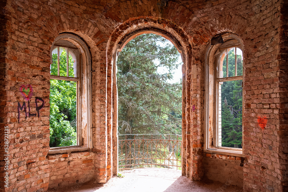 Abandoned red brick building windows without glasses, view from inside to green trees