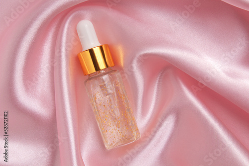 A face serum or natural essential oil lying on a pink fabric