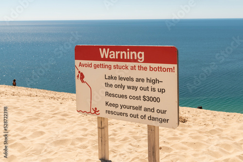 A warning sign urges caution on the steep slopes of Sleeping Bear Dunes National Seashore in Michigan.