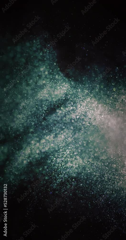 Glitter dust swirl. Particles background. Bokeh light texture. Defocused green blue orange bubbles splash on dark black abstract overlay. Vertical video. Shot on RED Cinema camera. Glitter dust swirl. Particles background. Bokeh light texture. Defocused green blue orange bubbles splash on dark black abstract overlay. Vertical video. Shot on RED Cinema camera.