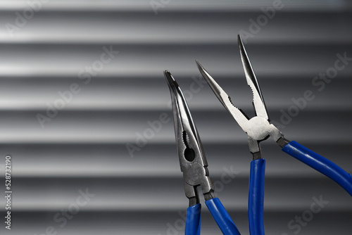 Blue long nose pliers on gray background. Hand tools nose plier for work hold wood steel 
                  