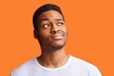 Portrait Of African Guy Having Doubt Looking Aside, Orange Background
