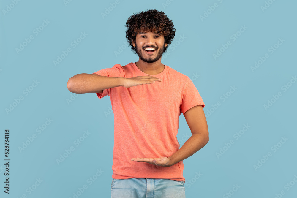 Cheerful handsome indian guy showing something invisible in his hands Cheerful handsome indian guy showing something invisible in his hands