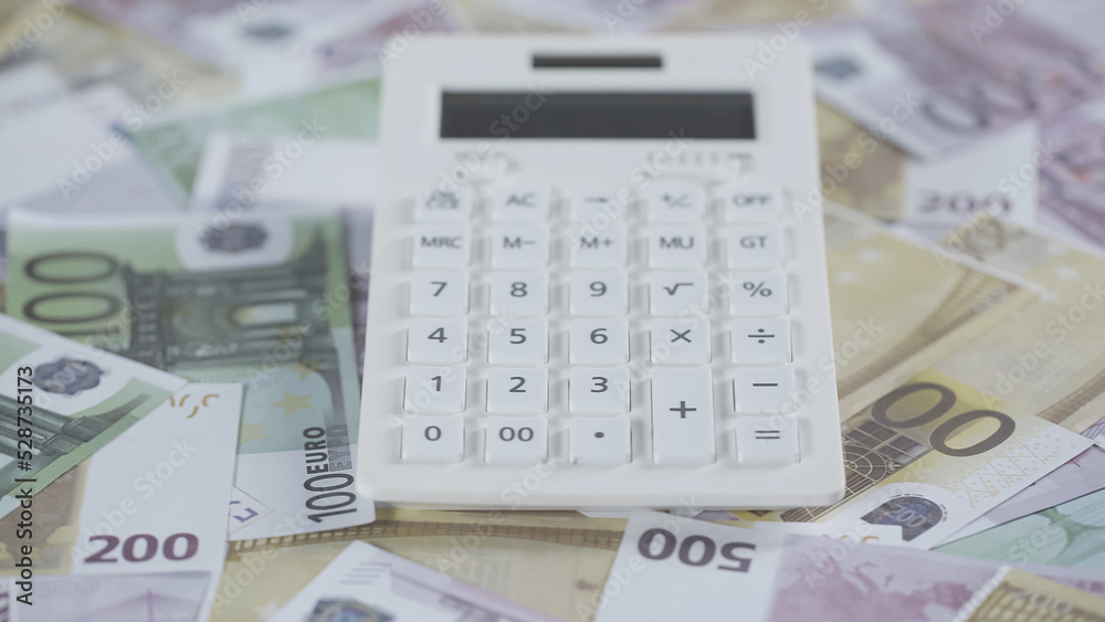 white calculator on scattered euro banknotes in studio white calculator on scattered euro banknotes in studio