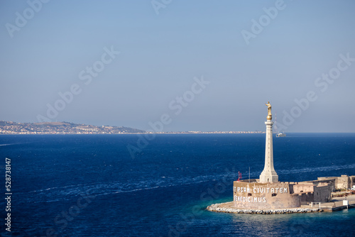Statue of La Madonnina del Porto and the cityscape of Messina, Sicily Italy seen from the water