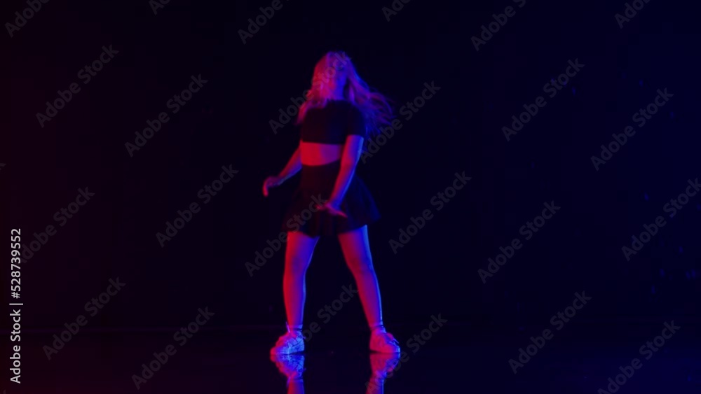 Young Woman with Long Blond Hairs Dances in Colorful Stage Lights in Studio Young Woman with Long Blond Hairs Dances in Colorful Stage Lights in Studio