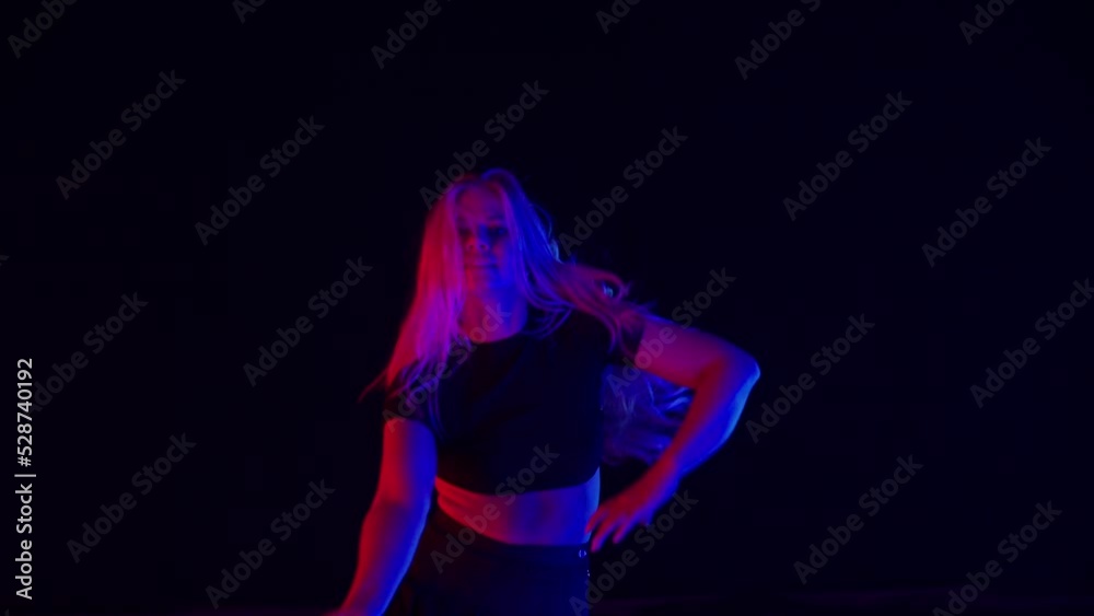 Young Woman with Long Blond Hairs Dances in Colorful Stage Lights in Studio Young Woman with Long Blond Hairs Dances in Colorful Stage Lights in Studio