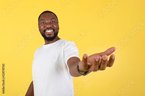 Happy Black Man Showing Invisible Object Standing Over Yellow Background