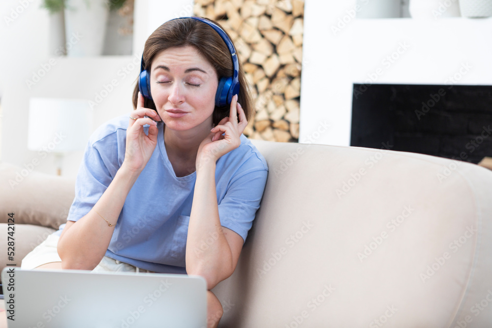 Naklejka premium Young attractive woman in headphones listening to music during break of studying online at home. Distance education concept