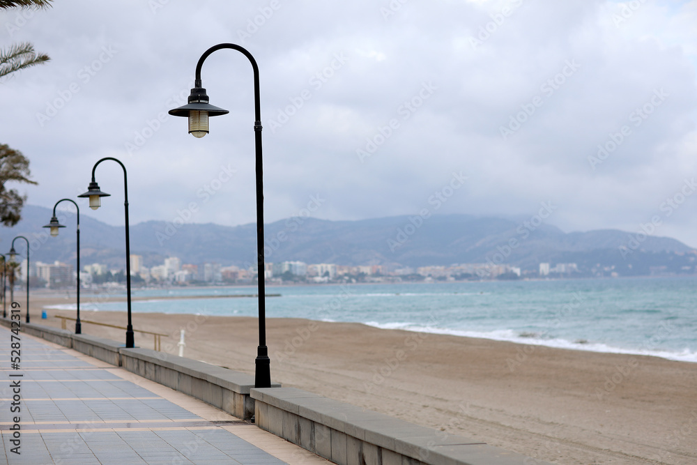Vintage street lamps on embankment and promenade of resort town. small town surrounded by mountains and Mediterranean sea in Spain, Europe