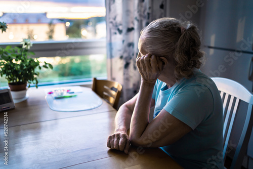 Sad old woman. Depressed lonely senior lady with alzheimer, dementia, memory loss or loneliness. Elder person looking out the home window. Sick patient with disorder. Pensive grandma. Widow with grief photo
