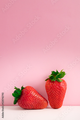 Two of freshly ripened strawberries on a pink background. Summer composition fruits, berries. 