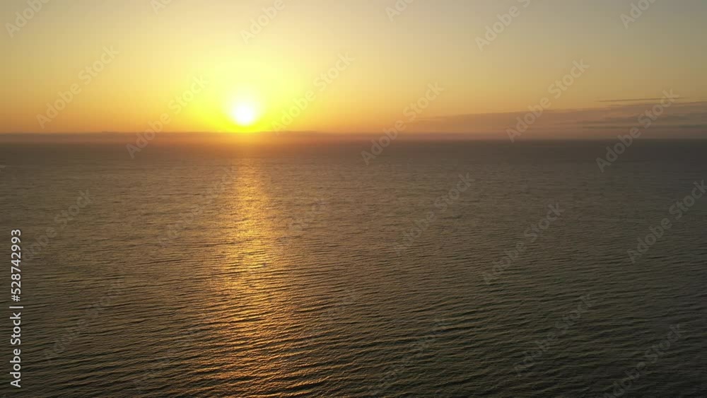 Beautiful sun rising over the calm ocean casting a golden reflection on waves below Beautiful sun rising over the calm ocean casting a golden reflection on waves below