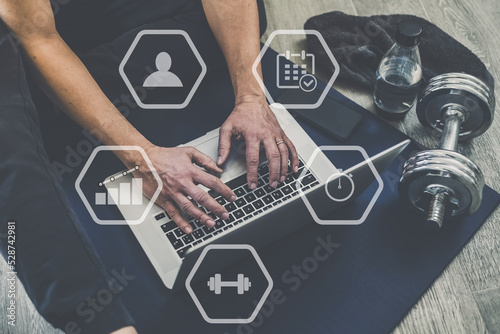 Man planning gym workout with laptop and smartphone. Watch online training sporty exercise, at home