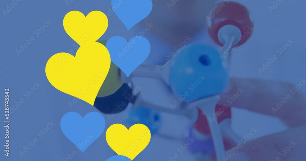 Animation of blue and yellow hearts over hand with model