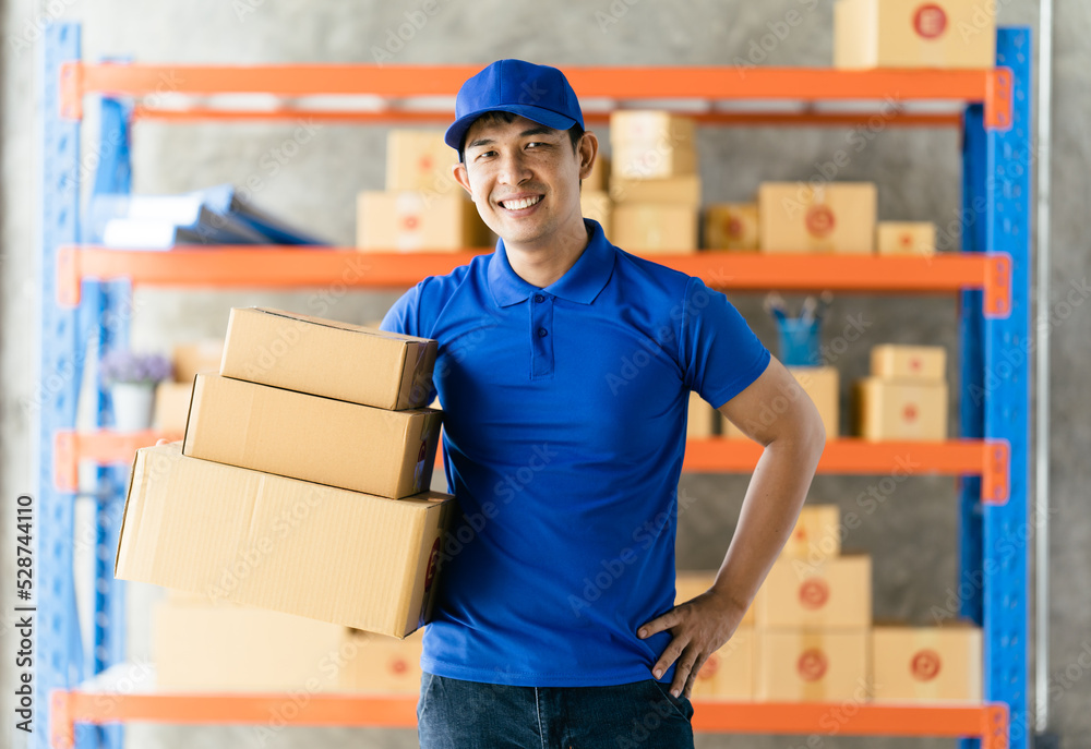 An Asian delivery man is working inside a warehouse. Delivery and service concept An Asian delivery man is working inside a warehouse. Delivery and service concept
