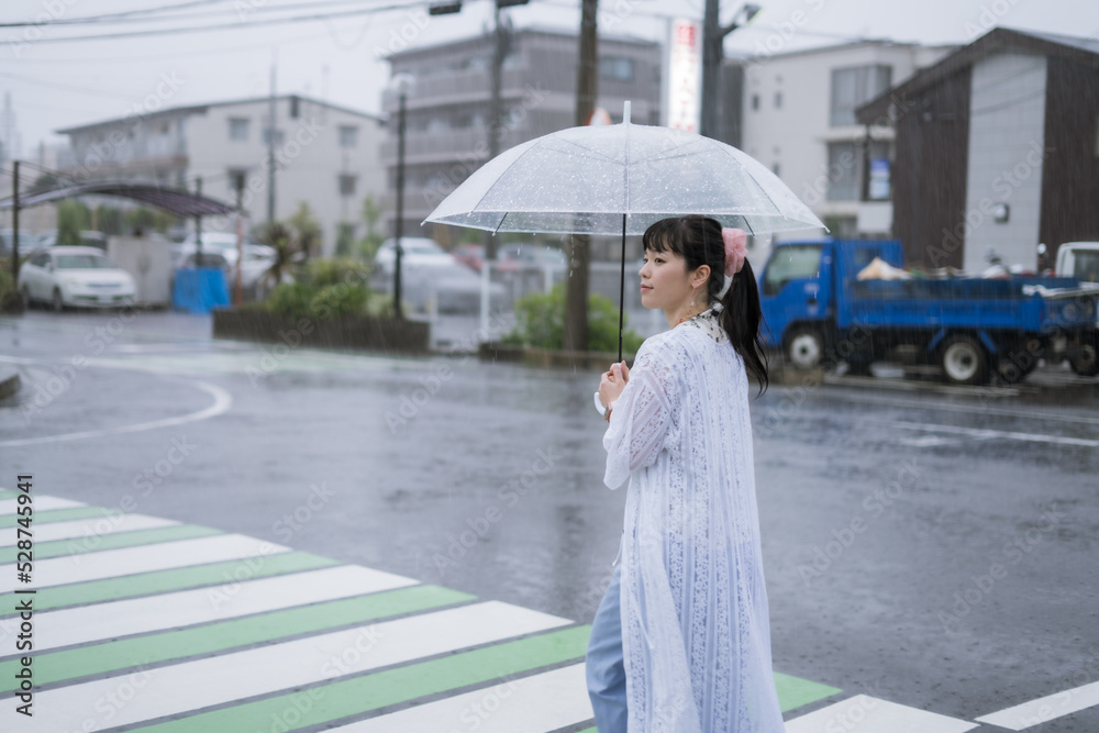 雨の中を傘をさして歩く女性