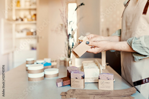 A soap maker girl holds a piece of freshly brewed handmade soap in her hands.The process of preparation and packaging.Home spa.Small business