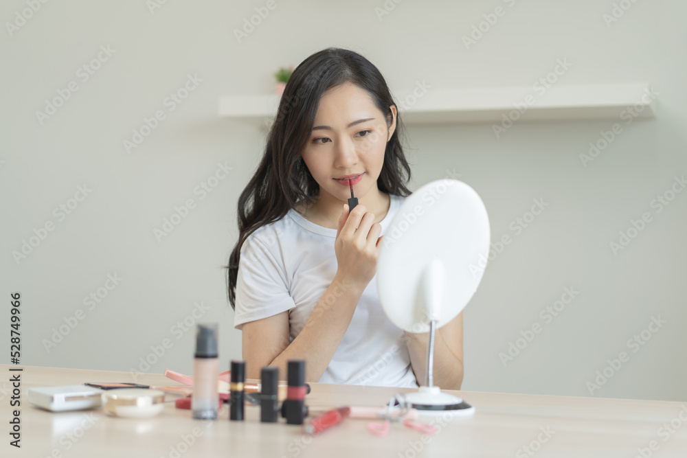 Daily makeup routine, Asian young women looks in the mirror during applying lipstick on her lip. Daily makeup routine, Asian young women looks in the mirror during applying lipstick on her lip.