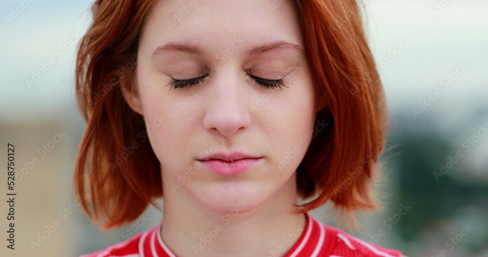 Closeup of redhead young woman looking to camera with wind blowing Closeup of redhead young woman looking to camera with wind blowing
