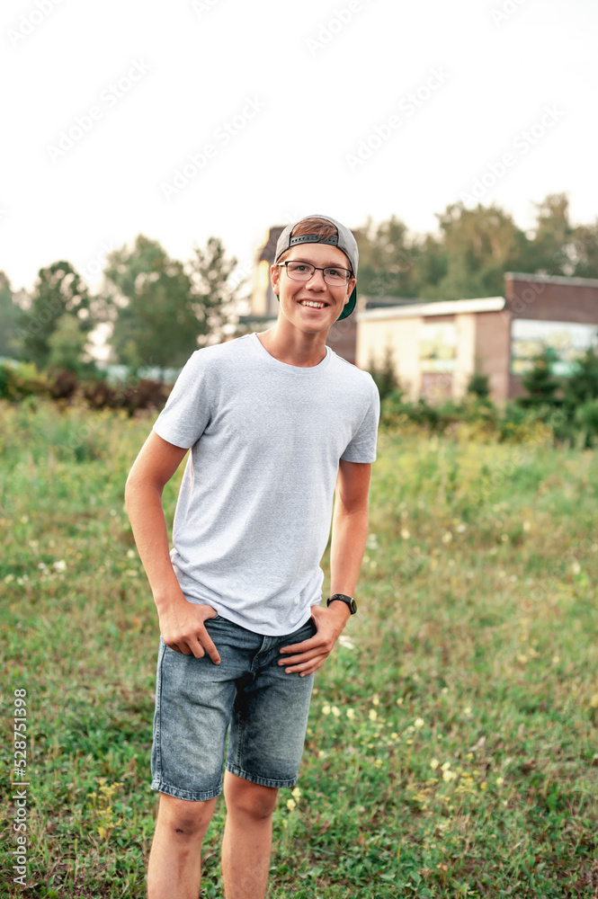 Attractive European teenager in glasses and a cap with a visor backwards, looks forward and